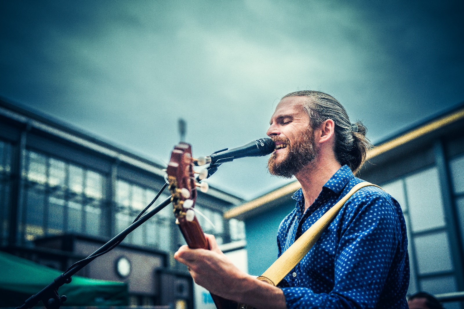 Mann mit Gitarre singt in ein Mikrofon