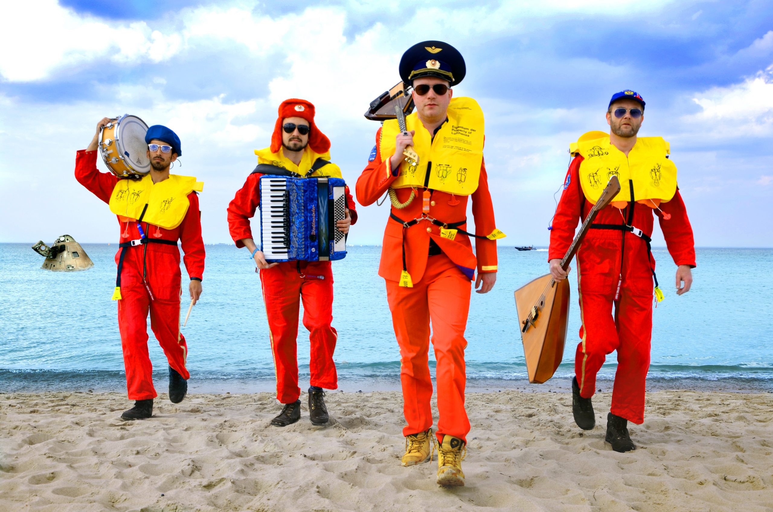 Vier Männer in Austronatuen-Anzügen und gelben Schwimmwesten. Jeder von ihnen halten ein Instrument in der Hand.