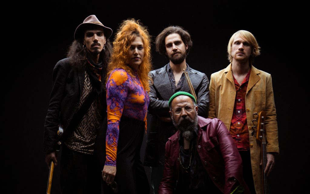 Vier Männer und eine Frau stehen vor einem schwarzen Hintergrund. 