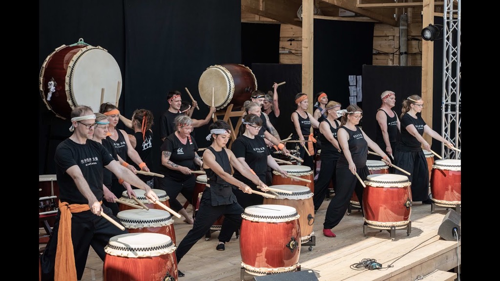 Eine Gruppe von schwarz gekleideten Menschen, die trommeln.