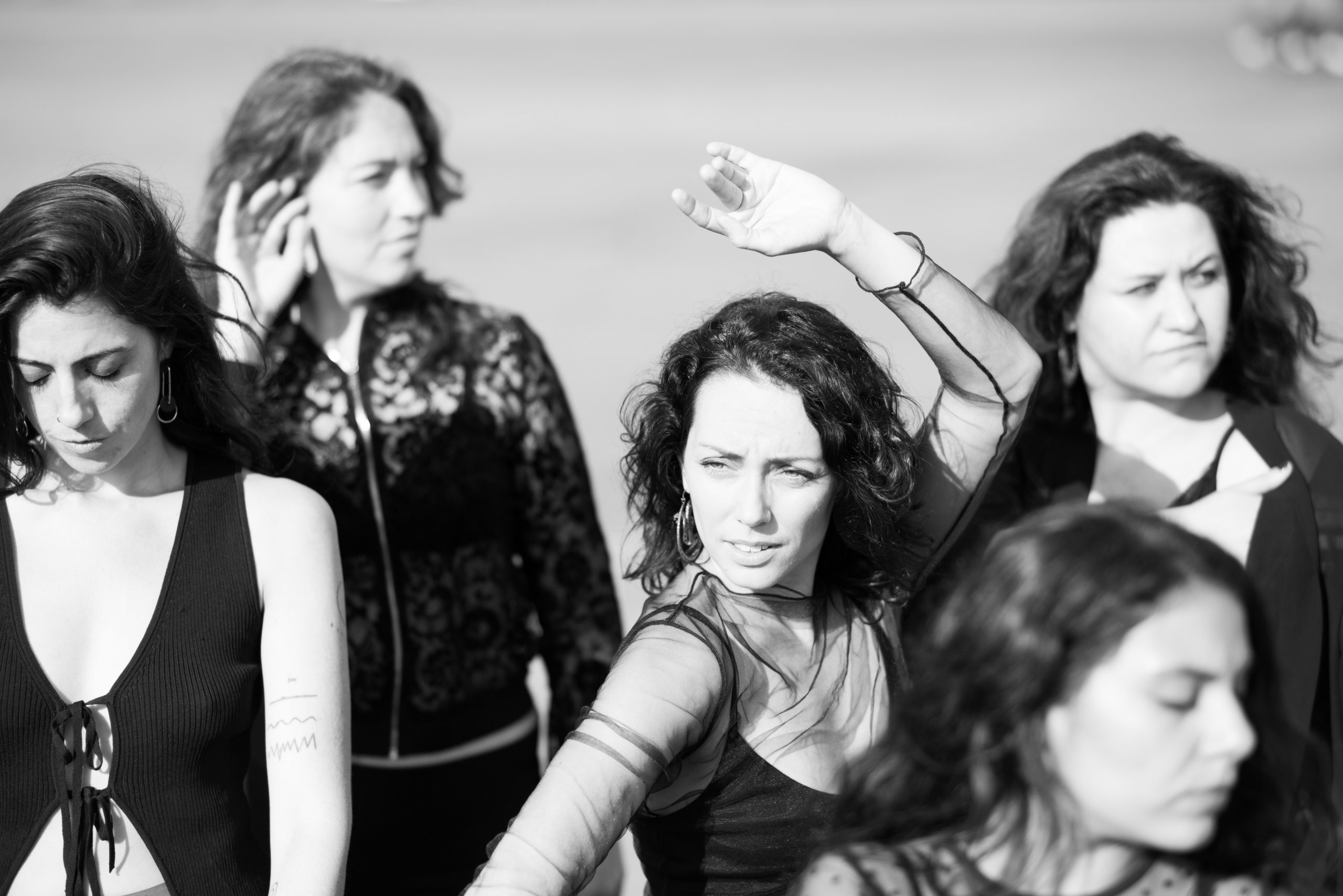 Eine Gruppe von Frauen in schwarzer Kleidung stehn zusammen und blicken in unterschiedliche Richtungen.